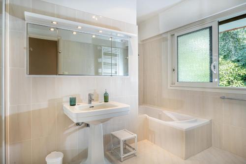 La salle de bains est pourvue d'un lavabo, d'une baignoire et d'un miroir. dans l'établissement Dream Villa 300m2 & stunning 4000m2 private garden, à Cannes