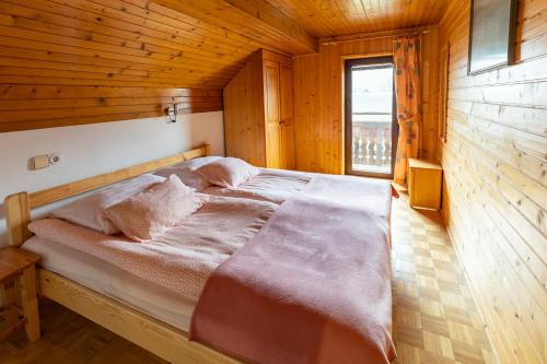 a bed in a wooden room with a window at Apartments Pri Urhu in Bohinj