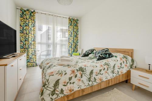 a bedroom with a bed and a tv and curtains at Apartament Flora - apartament blisko morza in Gdańsk