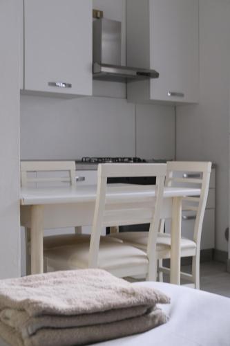 een witte keuken met een tafel en 2 stoelen bij casa margherita in Lodi