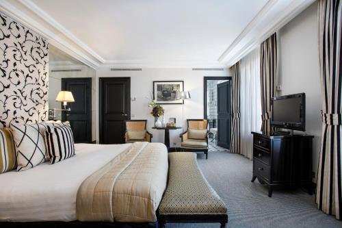 パリにあるカスティーユ パリ スターホテルズ コレツィオーネのベッドとテレビが備わるホテルルームです。