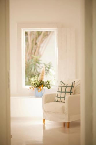 a living room with a white chair and a window at Octant Vila Monte in Moncarapacho