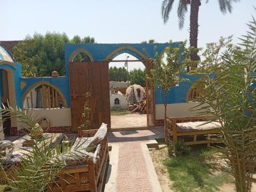 a blue building with a gate and benches in a yard at Golden Palace Family in Luxor