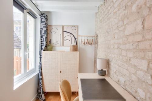een kamer met een tafel en een bakstenen muur bij Le Matilda - Appt Hypercentre 2 pers in Caen