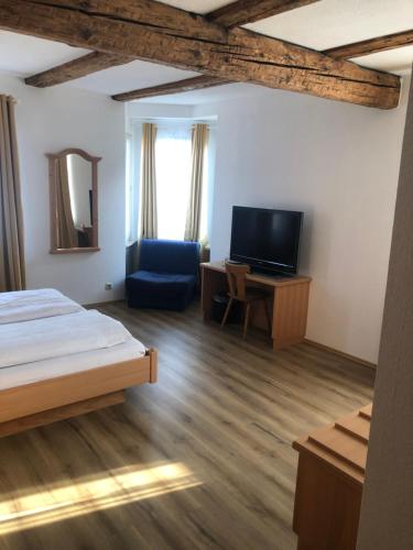 Schlafzimmer mit einem Bett, einem TV und einem Stuhl in der Unterkunft Brauereigasthof Hotel Schlüssel in Giengen an der Brenz