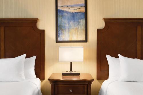a hotel room with two beds and a table with a lamp at Embassy Suites by Hilton Bloomington/Minneapolis in Bloomington
