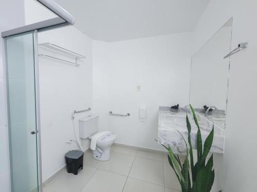 a bathroom with a toilet and a shower and a plant at Hotel Refugio in Maceió