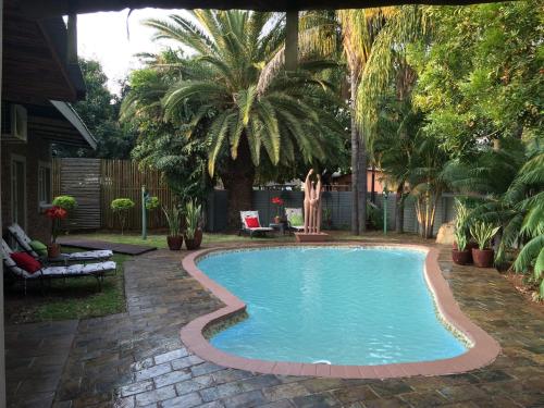 uma piscina num quintal com palmeiras em Zoete Rust Boutique Hotel em Lephalale