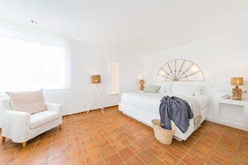 a white bedroom with a bed and a chair at Octant Vila Monte in Moncarapacho