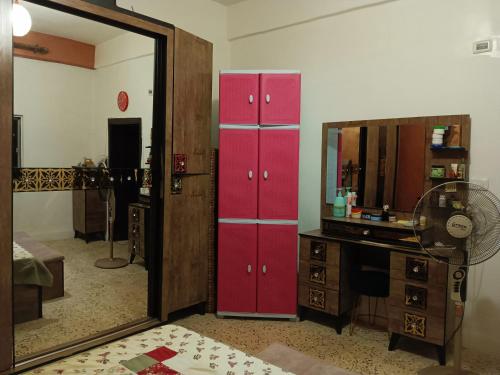 a dressing room with red cabinets and a mirror at Flowers apartment in Amman