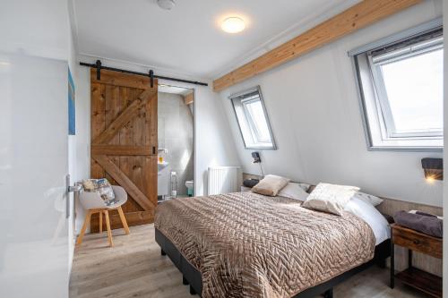 a bedroom with a bed and a sliding barn door at Wulpenweid Bed & Parking in Den Burg