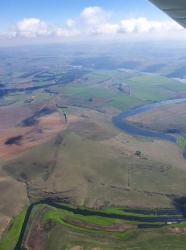 une vue aérienne d'un champ et d'une rivière depuis un avion dans l'établissement Hythe Cottages, à Mooirivier