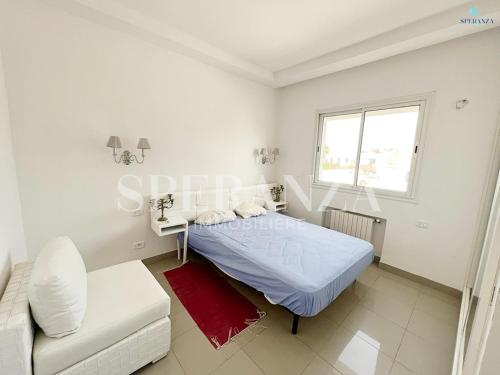 a white bedroom with a bed and a couch at Appartement cerise S+2 in Nabeul