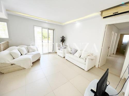 a white living room with white couches and windows at Appartement cerise S+2 in Nabeul