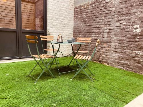 une table et des chaises assises sur une pelouse à côté d'un mur de briques dans l'établissement Villa Haze, à Tourcoing