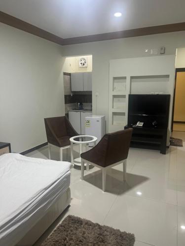 um quarto com uma cama e cadeiras e uma cozinha em الراحة بلازا للشقق المفروشة em Sharurah