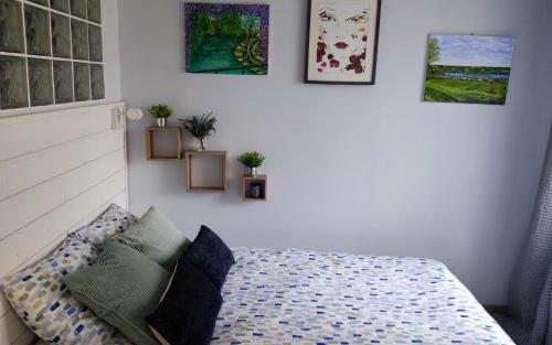une chambre avec un lit et des tableaux au mur dans l'établissement Petit cottage, à Saint-Pierre-la-Garenne