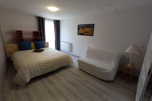 a bedroom with a bed and a chair and a window at Gîte Angevin 2 à 4 personnes in Montreuil-Bellay