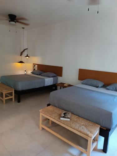 a bedroom with two beds and a bench in it at jungle lodge in Cancún
