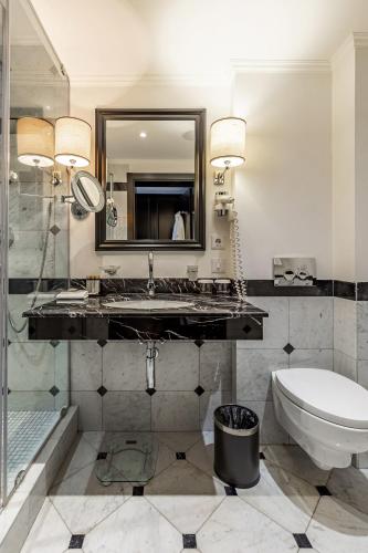 a bathroom with a sink and a toilet and a mirror at Maidan Palace Hotel in Kyiv