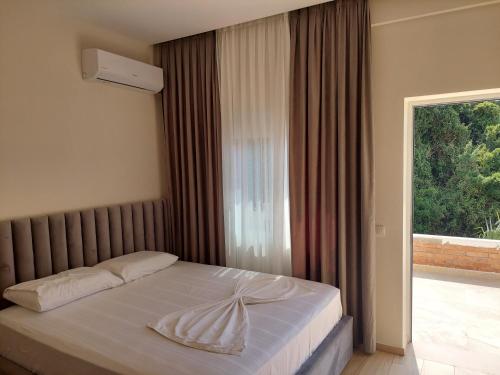 een slaapkamer met een bed en een groot raam bij SOLE INN in Vlorë