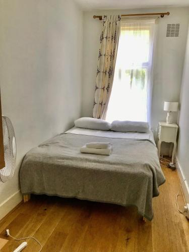 um quarto com uma cama grande e uma janela em Spacious 3 Bed Room Flat in South West London em Londres