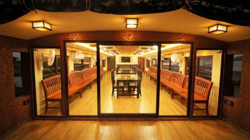 um quarto com portas de vidro e uma mesa e bancos em Kalappura Houseboats & Tours em Alappuzha