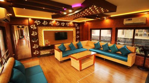 a living room with blue couches and a television at Kalappura Houseboats & Tours in Alleppey