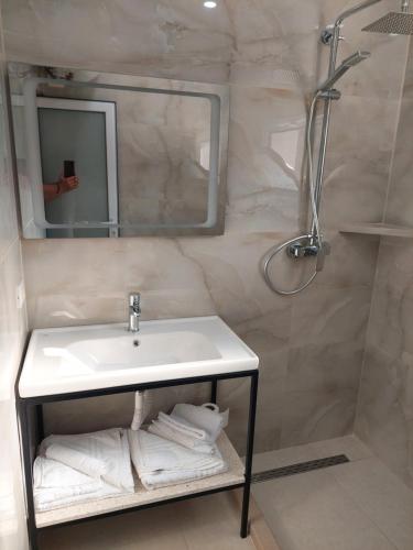 een badkamer met een wastafel, een douche en een spiegel bij SOLE INN in Vlorë