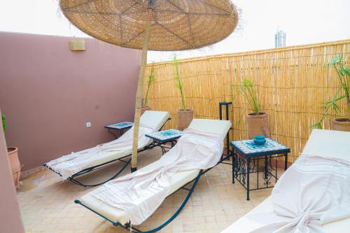 a group of beds on a patio with an umbrella at Riad Dar Zaouia in Marrakech