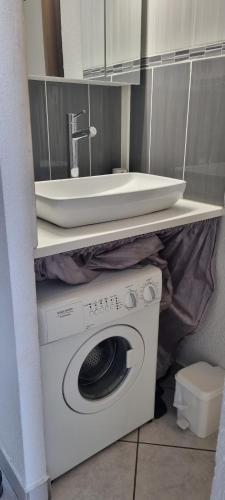 une salle de bain avec une machine à laver et un lavabo dans l'établissement Studio village naturiste vue sur port nature 7, au Cap d'Agde