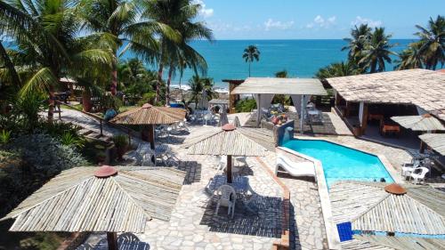 una vista aerea di un resort con piscina e ombrelloni di Pousada Enseada do Sol a Jacumã