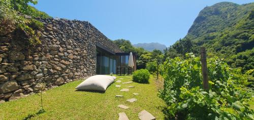 uma almofada sentada na relva ao lado de um edifício de pedra em Terrabona Nature & Vineyards em Boaventura