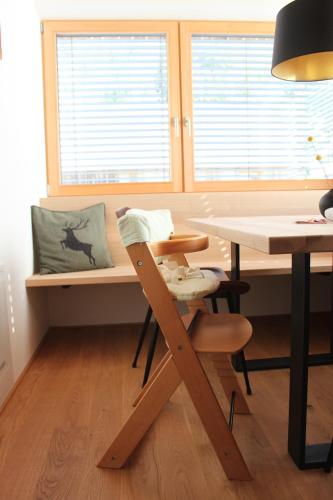a wooden chair sitting next to a desk with windows at Kanis 80 in Schnepfau