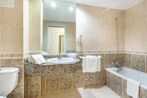 een badkamer met een wastafel, een bad en een toilet bij Hotel Kilimanjaro in El Arenal