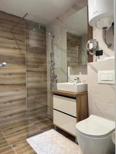 y baño con ducha, aseo y lavamanos. en Hotel Djina - Kopaonik, en Kopaonik