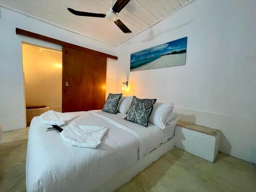 a bedroom with a white bed with a ceiling fan at Posada Lagunita in Los Roques