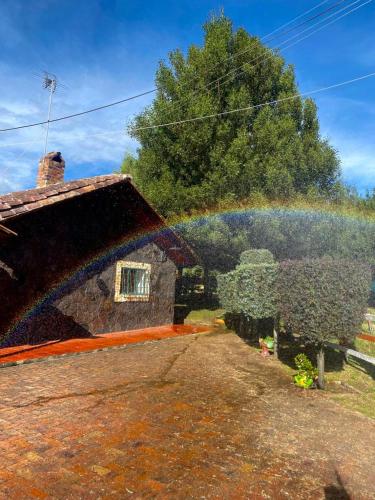 a rainbow over a garden with a house at El Nogal finca-hotel in Firavitoba