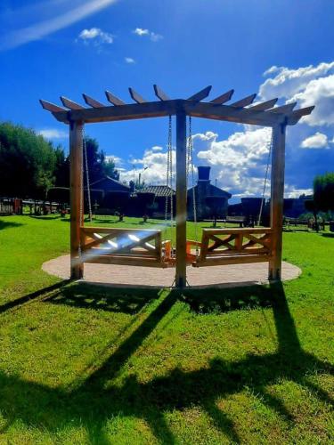 a wooden swing in a park with a sky at El Nogal finca-hotel in Firavitoba