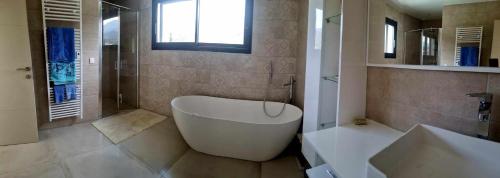 La salle de bains est pourvue d'une grande baignoire blanche et d'un lavabo. dans l'établissement Chambres d hôtes de luxe, spa, piscine, entre mer et montagne, à Villelongue-dels-Monts