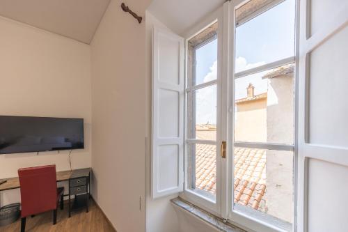 a room with a window and a desk and a table with a television at The House of Thrones in Viterbo