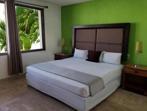 1 dormitorio con 1 cama grande y pared verde en Nirvana Hotel - Cancun Hotel Zone, en Cancún