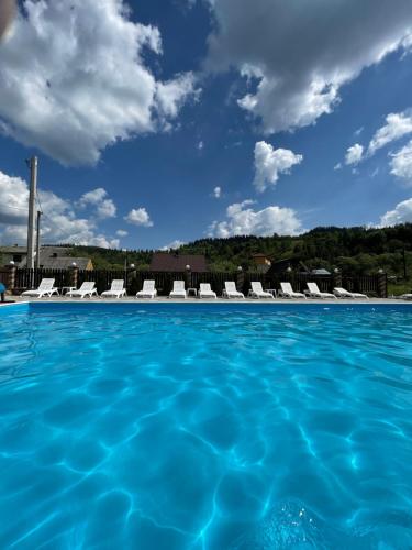 a swimming pool with chairs and a blue sky at Zarichna Lyks in Slavske