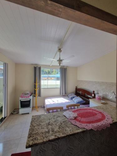 a living room with a bed and a table at Kitnets da Tia Zeni in Arraial do Cabo