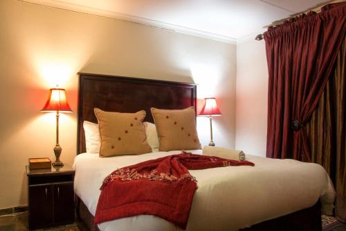 a bedroom with a large bed with two lamps at Zoete Rust Boutique Hotel in Lephalale