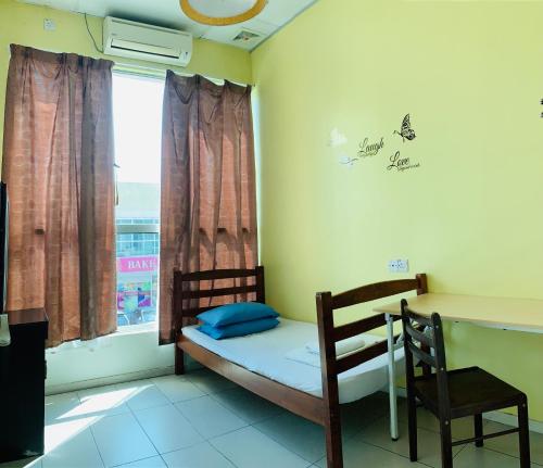 Habitación pequeña con cama, escritorio y ventana. en Prima B&B Hostel, en Sandakan