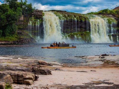 a group of people on a boat in front of a waterfall at Waka Wená in Santa Elena de Uairén