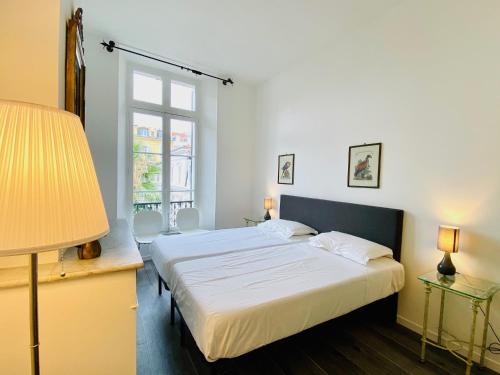 une chambre avec deux lits et une lampe et une fenêtre dans l'établissement Cozy 2 bedroom apartment in the centre of Cannes near the CROISETTE, à Cannes