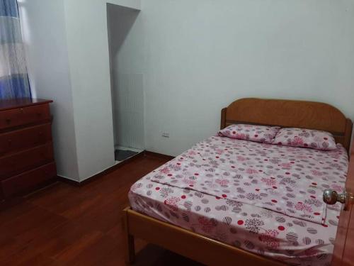 a bedroom with a bed with pink sheets and a dresser at Alojamiento Casa Grande in Iquitos