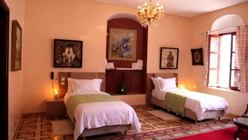 1 dormitorio con 2 camas y lámpara de araña en Ryad 91 en Casablanca